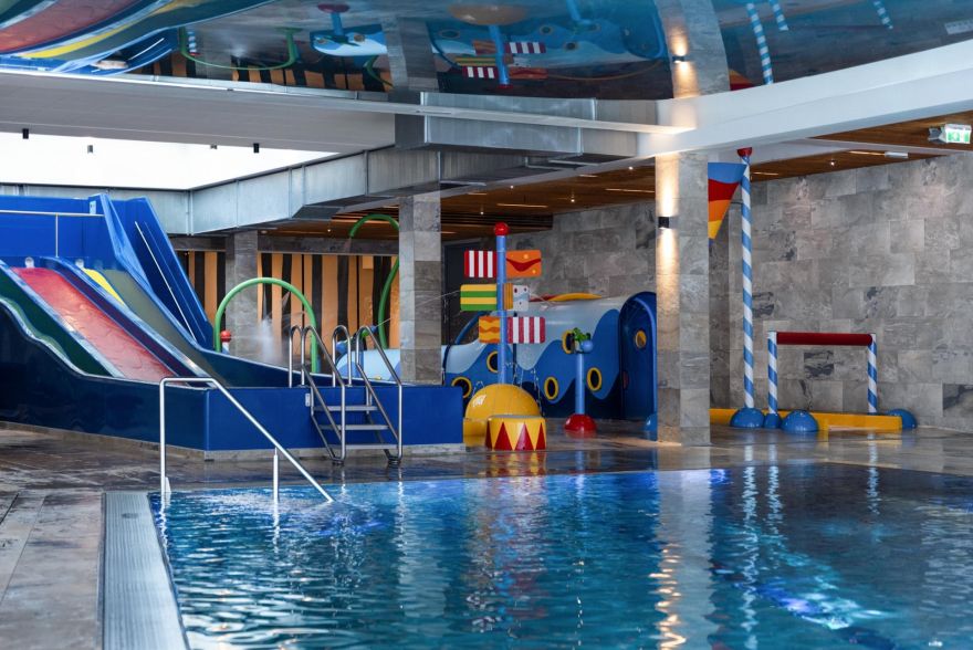 Bereich des Indoor-Kinderpools mit Wasserrutschen, Spielzeug und großem Schwimmbecken.