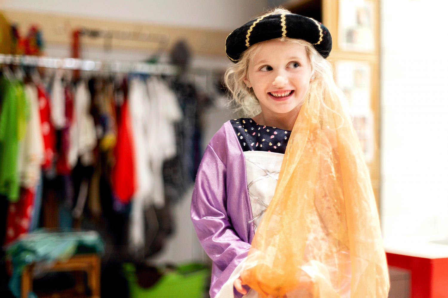 Nahaufnahme eines jungen Mädchens, das als Prinzessin verkleidet in die Kamera grinst. 