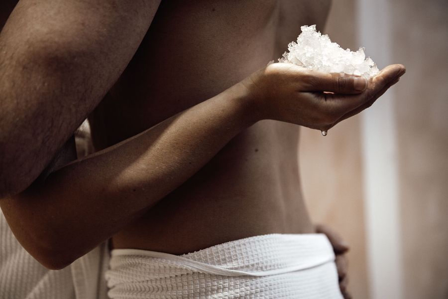 Close-up of a hand behind a back, holding salt crystals.