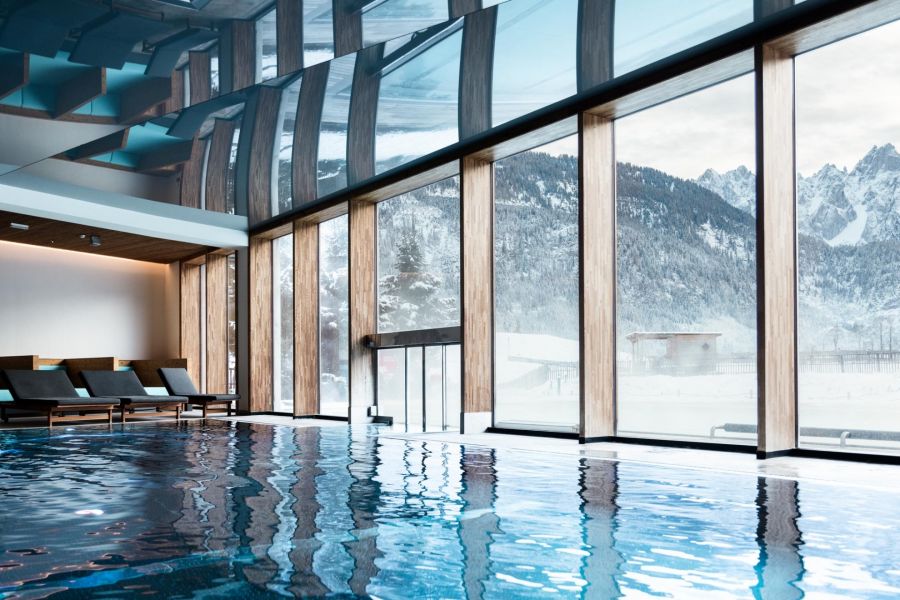 Indoor pool with a view outside into the snow-covered nature and mountains.