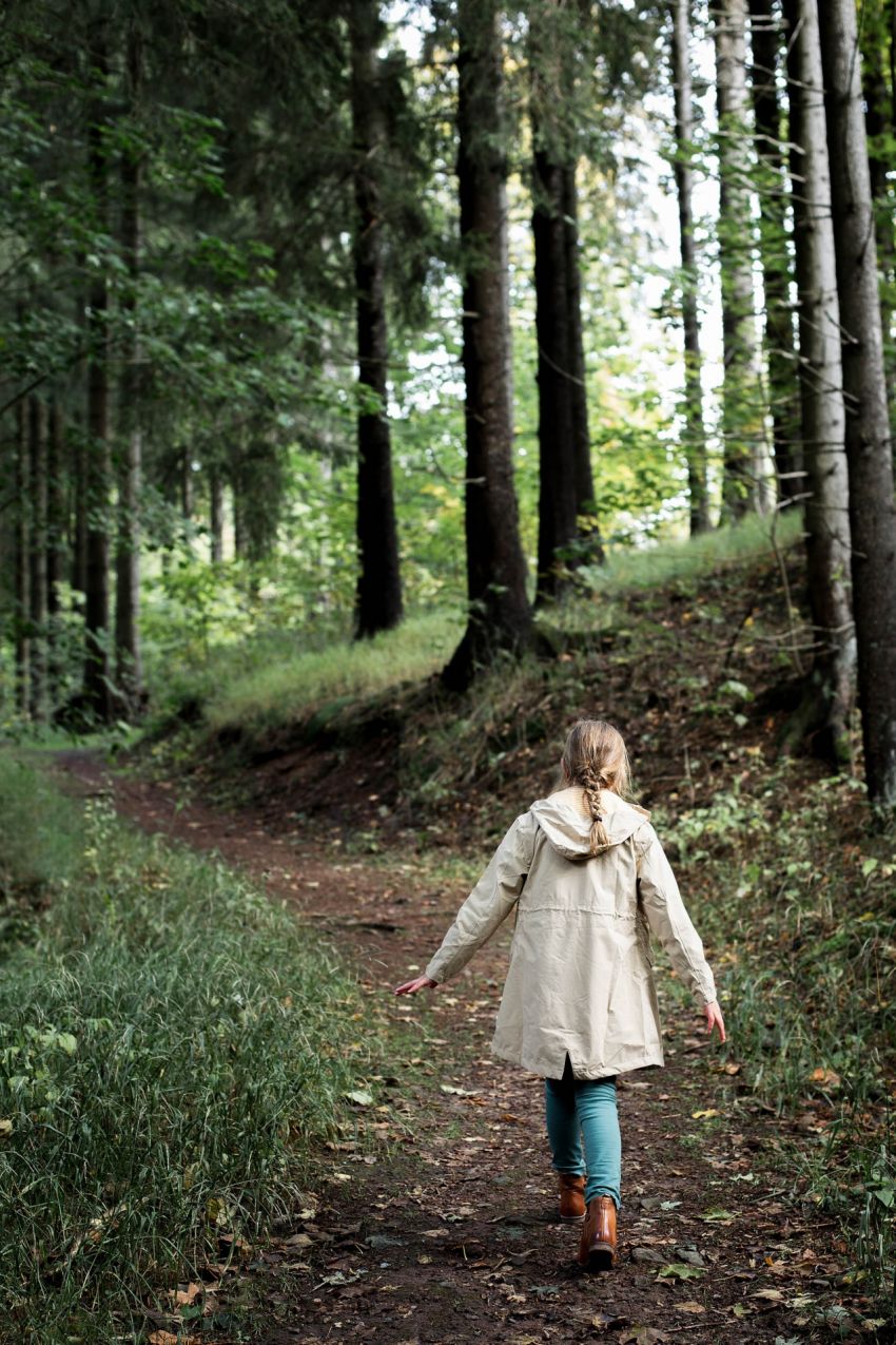 A girl walking up a forest path.